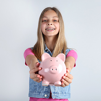 girl with braces holding piggy bank