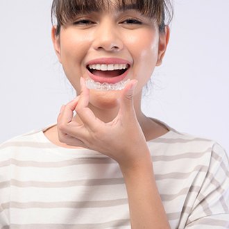 Portrait of smiling woman holding Invisalign in Derry