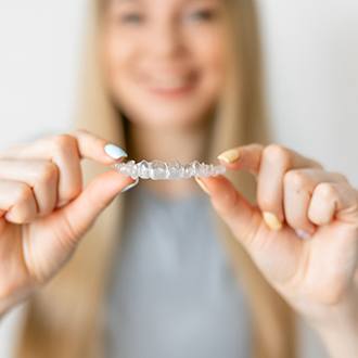 Closeup of patient holding Invisalign in Derry