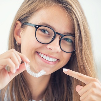 Smiling woman points to her Invisalign in New Hampshire 