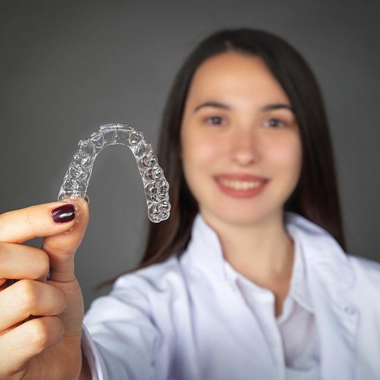 Woman holding up an Invisalign tray