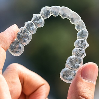 Hand holding up a clear aligner tray