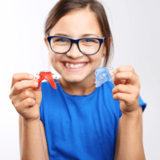 Child holing up two orthodontic appliances