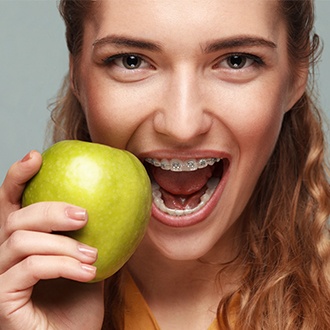 Woman with braces biting into an apple