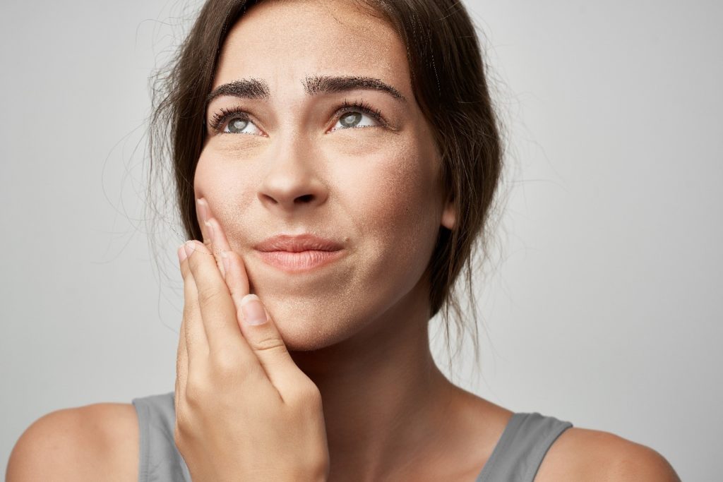 Woman experiencing soreness from Invisalign aligners