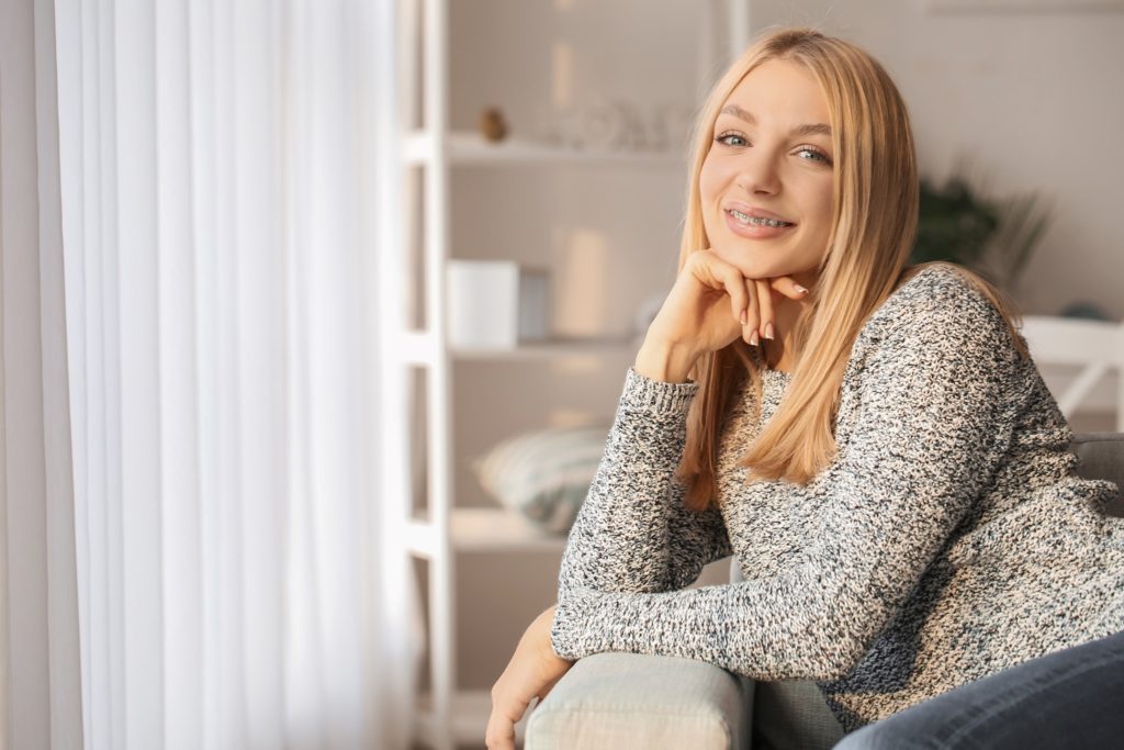 Closeup of young woman smiling in sweater on couch