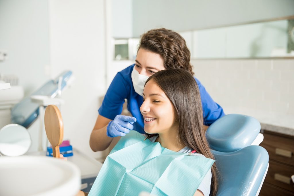 Orthodontist and patient with braces smiling