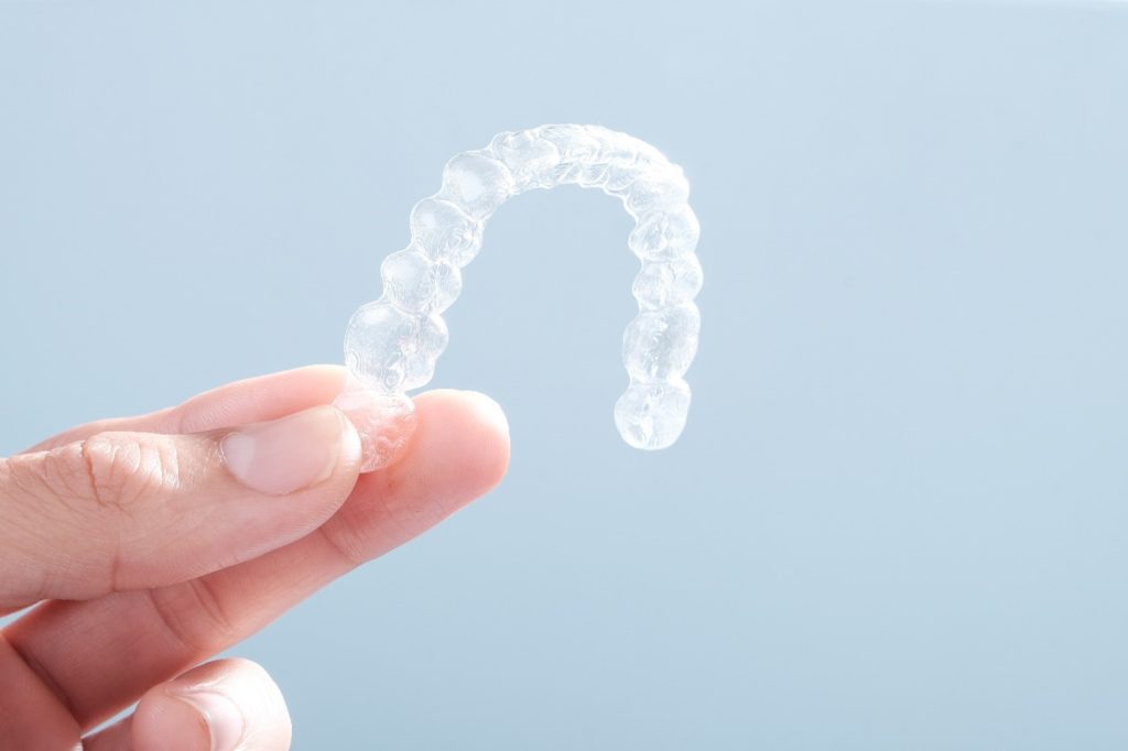 Patient holding Invisalign clear aligner for top teeth