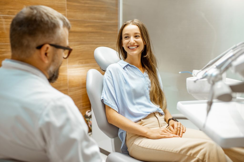 Woman smiling at orthodontist while sitting in treatment chair